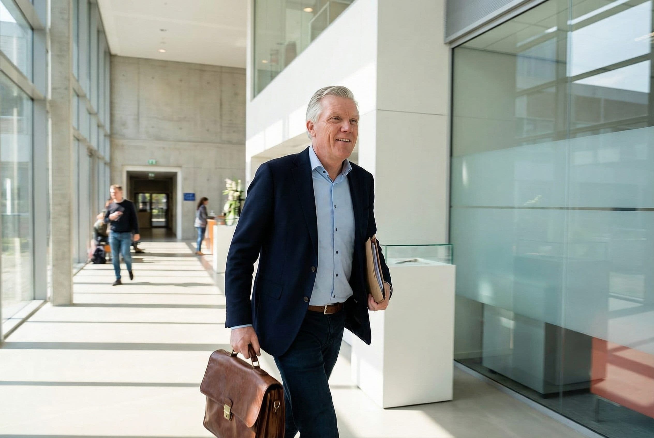 Stephan loopt door een stadskantoor met aktetas, op weg naar een afspraak